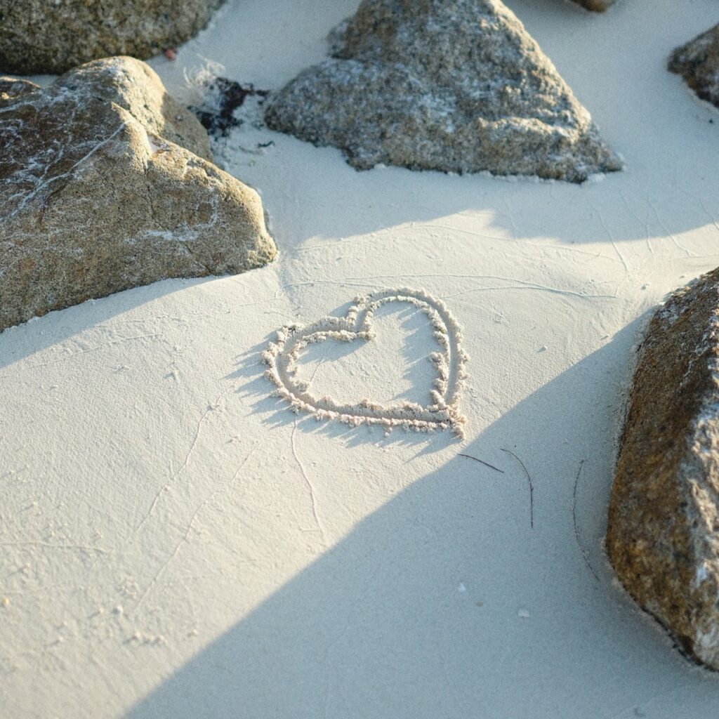 Heart etched into sand between rocks